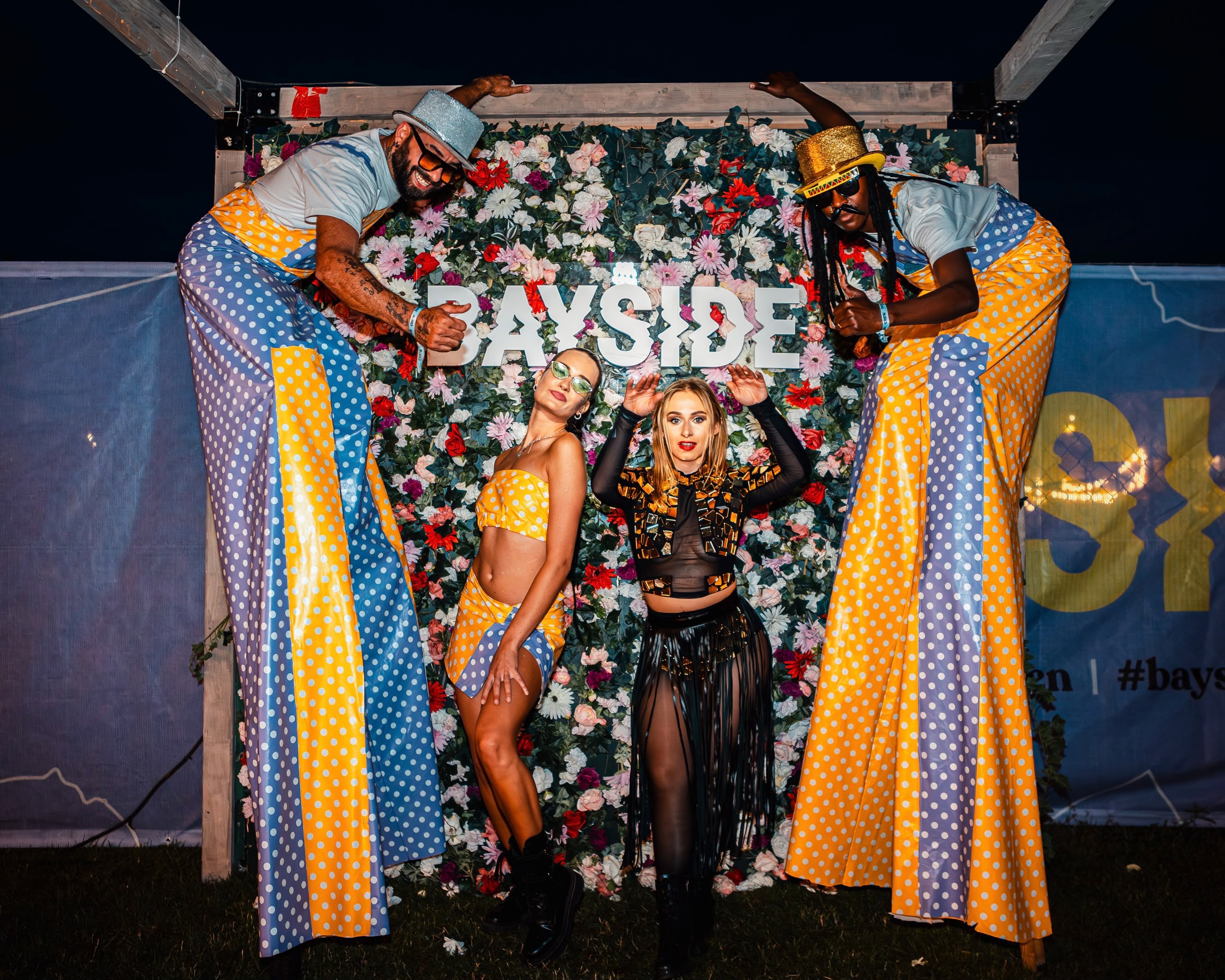 Zero5Show stilt walkers and dancers in front of a flower wall